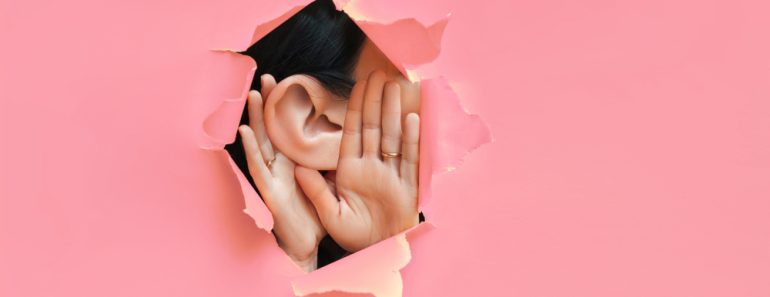 Female,Ear,And,Hands,Close-up.,Copy,Space.,Torn,Paper,,Pink