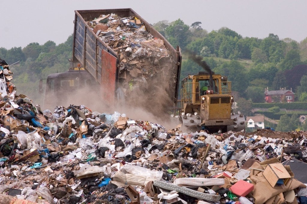 A bulldozer and garbage truck on a landfill waste site