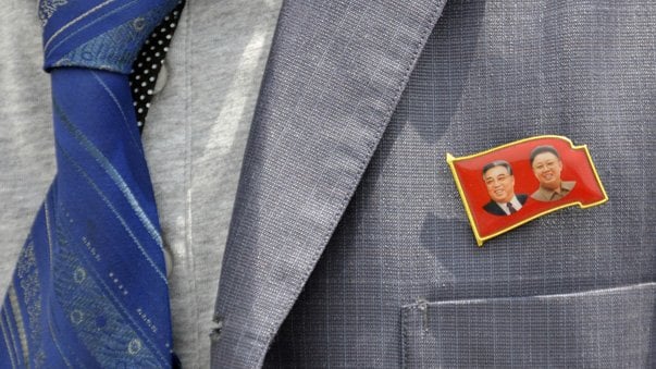 A participant wears a badge showing former North Korean leaders Kim Il Sung and Kim Jong Il during the opening ceremony of a new dock at the port of Rajin July 18, 2014. The dock was jointly built with Russia after last year's completion of a railway link to North Korea, holding out the prospect of increased trade for the reclusive nation with its biggest neighbours after years of international sanctions. Picture taken July 18, 2014. REUTERS/Yuri Maltsev