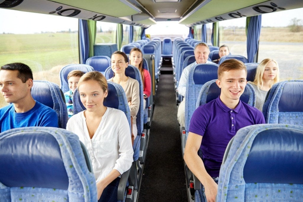 transport, tourism, road trip and people concept - group of happy passengers or tourists in travel bus