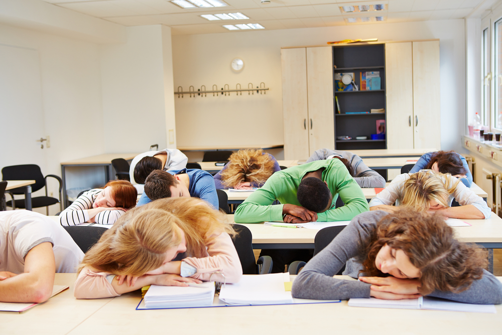 Many tired students sleeping in classroom with their heads on the table - Image( Robert Kneschke)s