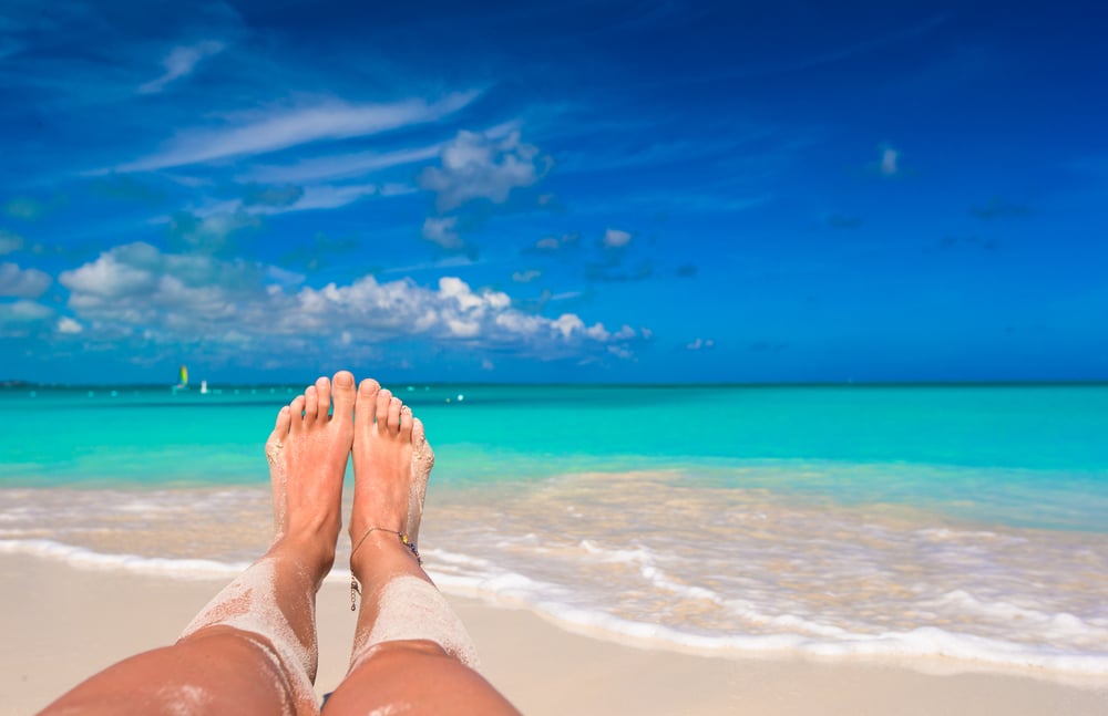 Pés femininos na praia de areia branca - imagem (TravnikovStudio) s