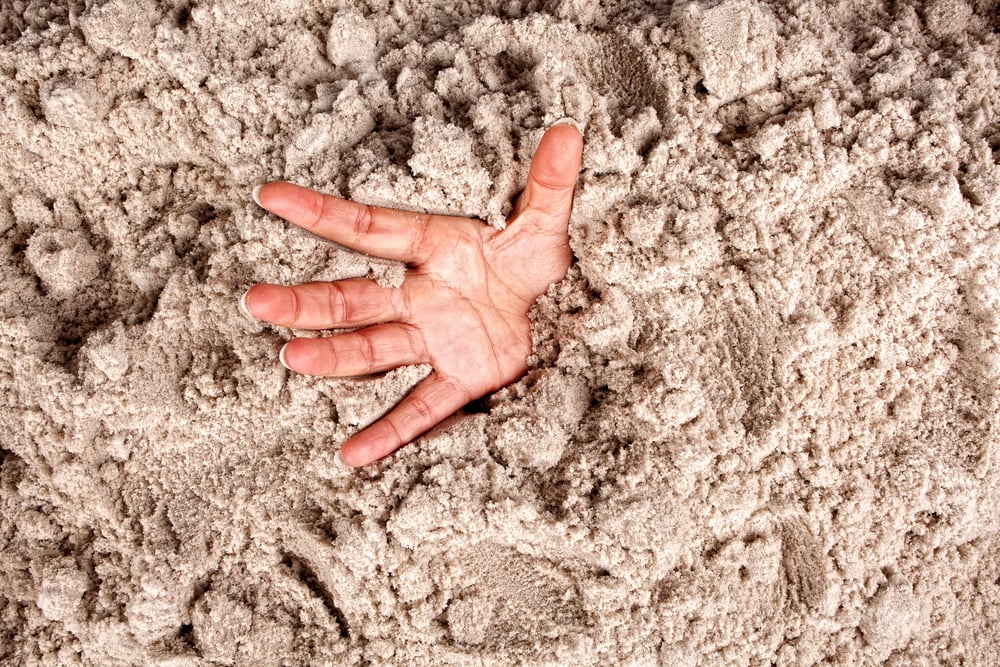 Hand on a beach sinking or drowning in quicksand - Image(Anneka)s