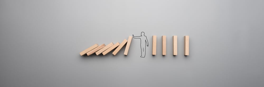 Wide cropped image of the outline of a businessman stopping the domino effect on gray background. - Image(Gajus)s