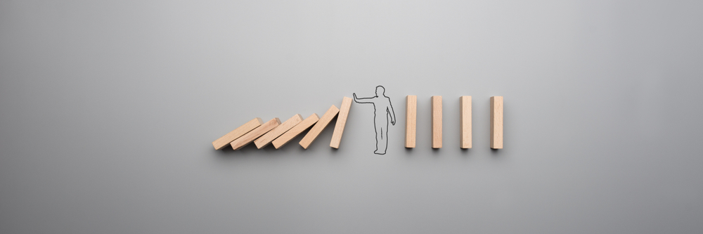 Wide cropped image of the outline of a businessman stopping the domino effect on gray background. - Image(Gajus)s