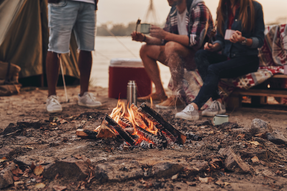 Ótima noite quente.  Close-up de jovens comendo marshmallows assados ​​enquanto acampava perto do lago - imagem (G-Stock Studio) s