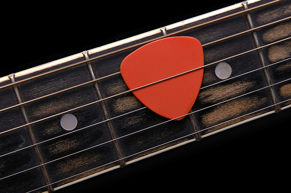 Orange guitar pick on the fingerboard - Image( Oleg Belov)s