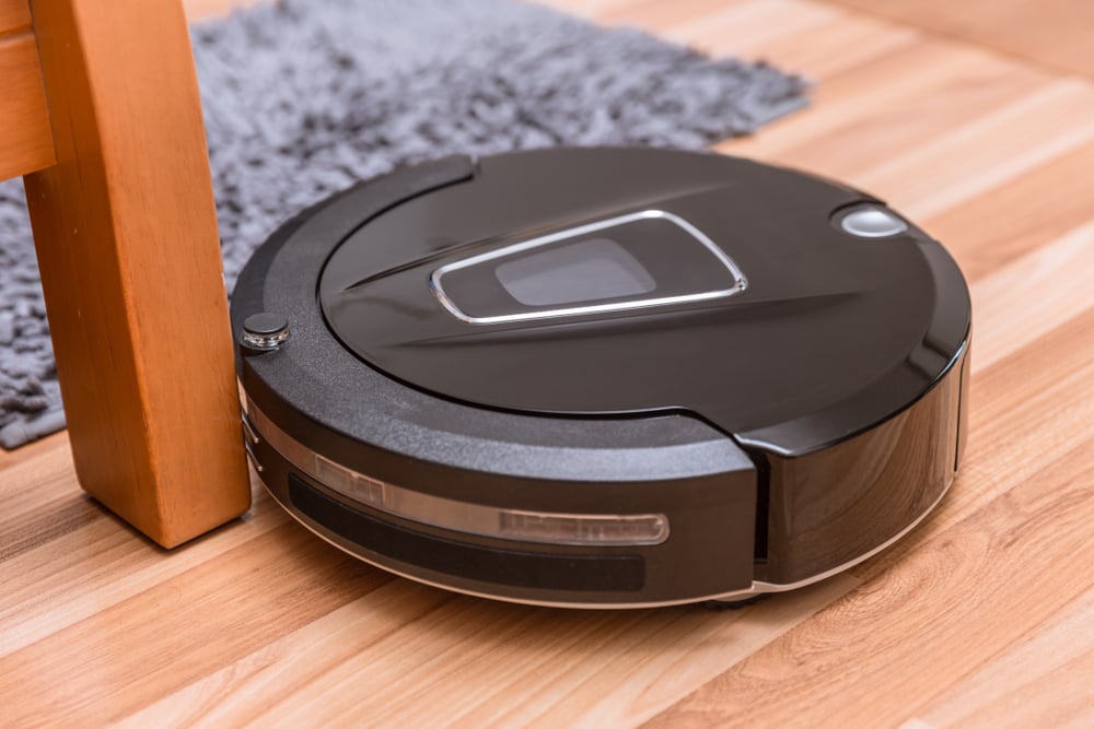 Robot vacuum cleaner on laminate wood floor with carpet cleaning - Image( Quality Stock Arts)S