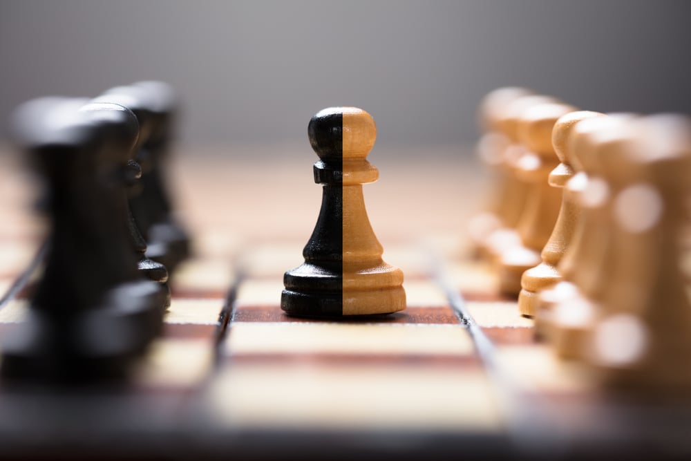 Closeup de peão de duas cores no meio de outras peças de xadrez a bordo do jogo - Imagem (Andrey_Popov) s