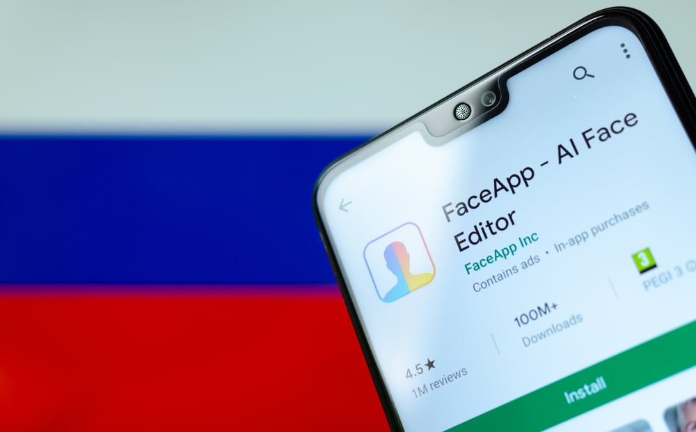 FaceApp logo na tela do smartphone com a bandeira da Rússia no fundo desfocado por trás (Ascannio) S