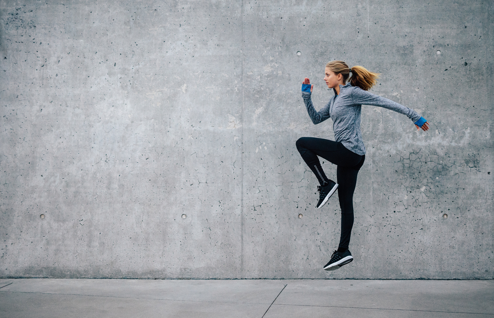 Side view shot of fit young woman doing cardio interval training against grey background( Jacob Lund)S