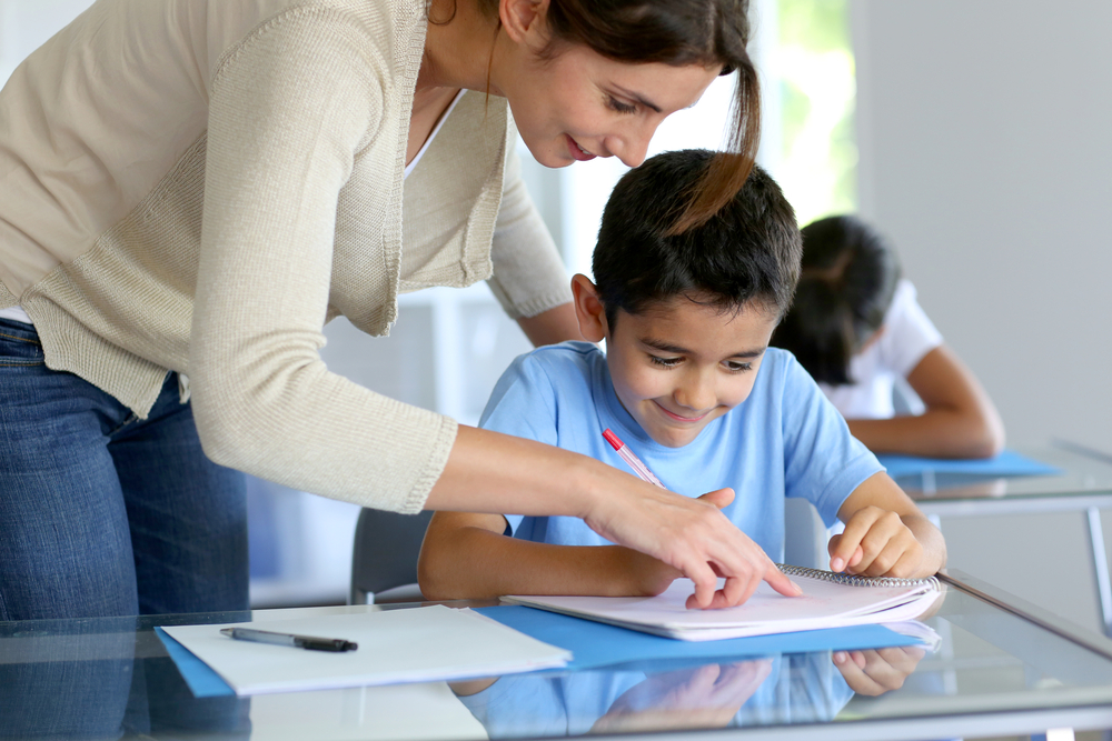 Teacher helping young boy with writing lesson - Image(goodluz)s