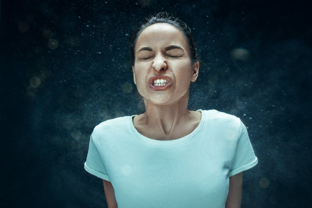 Young funny woman sneezing with spray and small drops, studio portrait on black background(Master1305)s