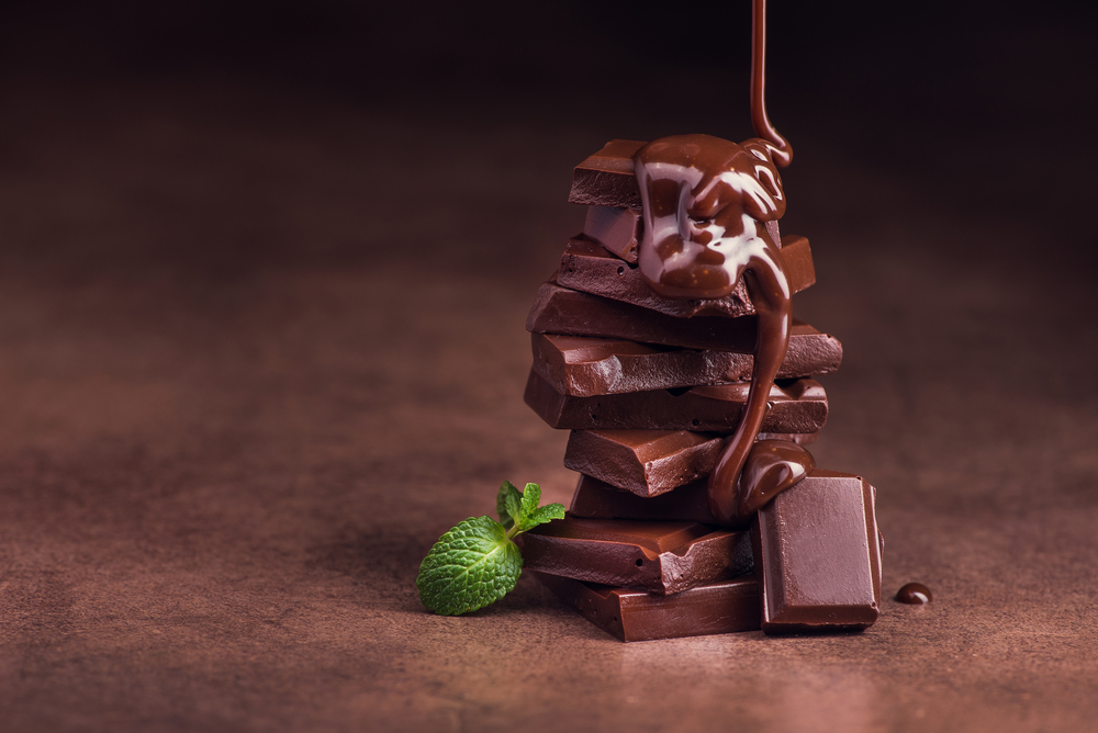 melted chocolate pouring into a piece of chocolate bars with green mint leaf on a table - Image( Dima Sobko)s