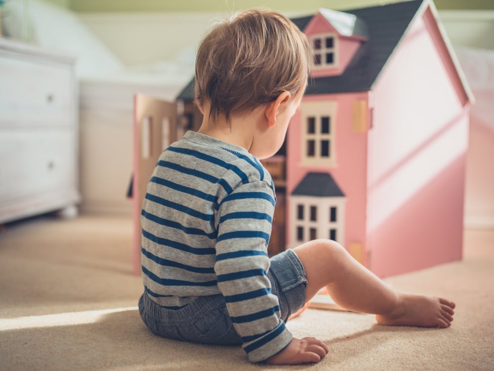 cute gender confident little boy is busting stereotypes and socially imposed expectations by playing with a big pink doll(Lolostock)S