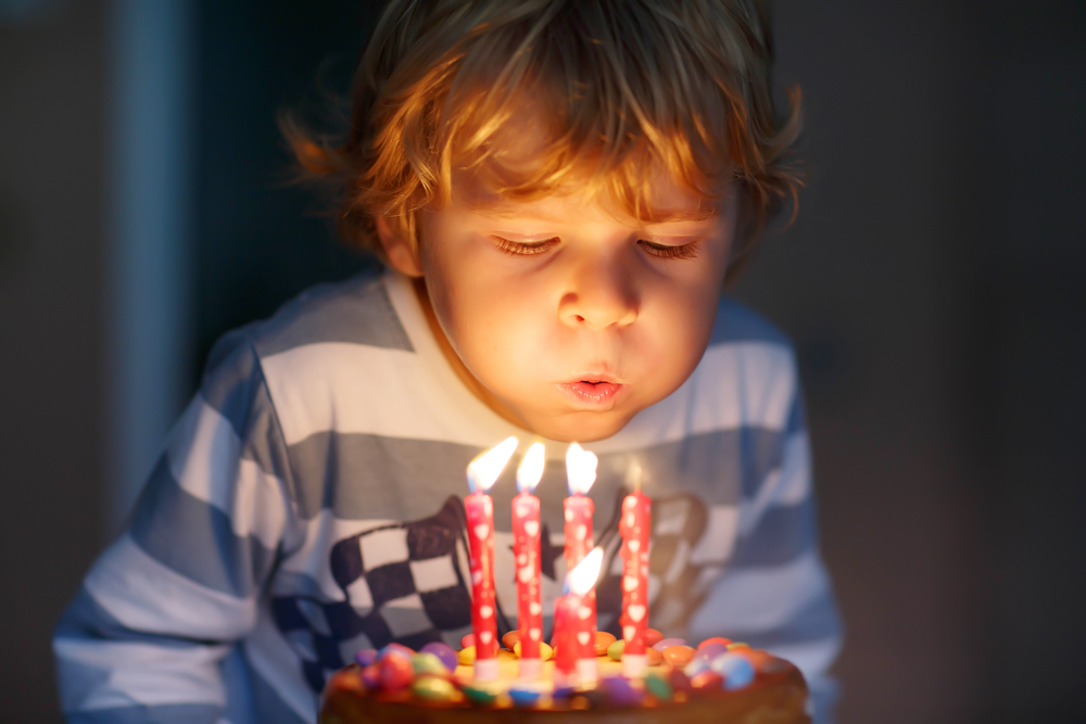 Adorável criança de quatro anos comemorando seu aniversário e soprando velas (Romrodphoto) s
