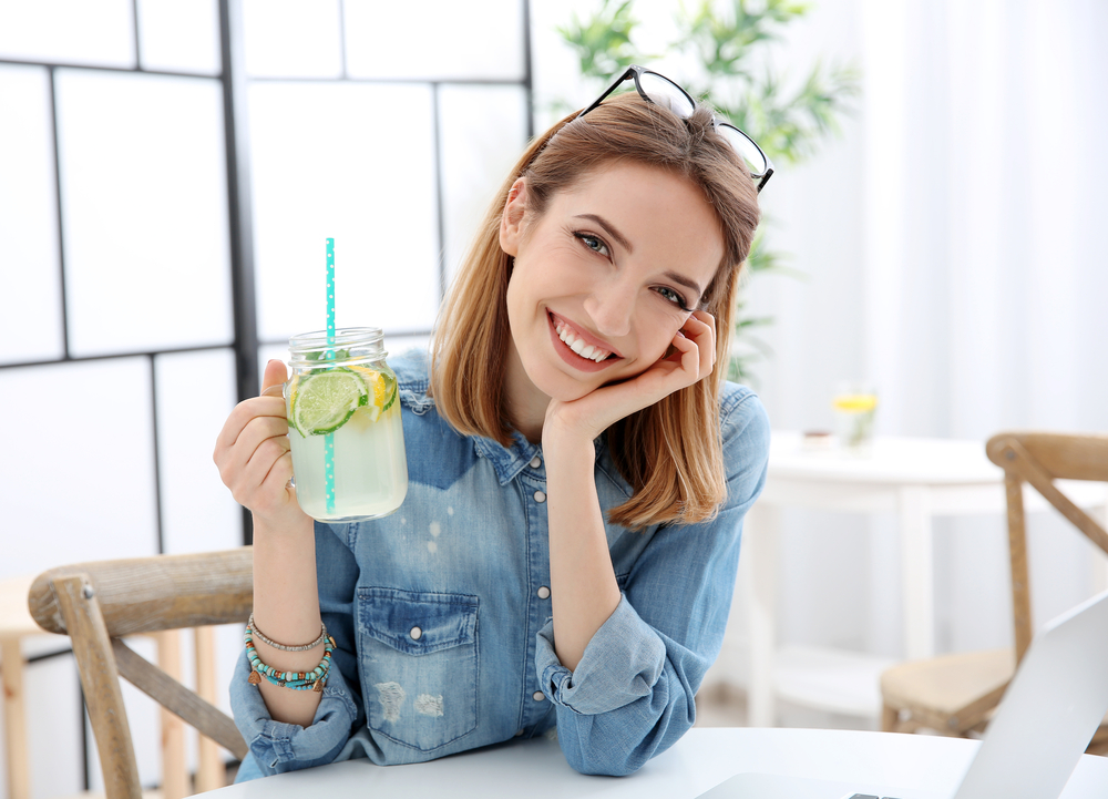 Beautiful young woman with lemonade and laptop in cafe(Africa Studio)s