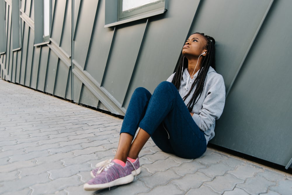 Depression teen african american girl listening to music and sitting lonely looking up(Andrii Kobryn)s