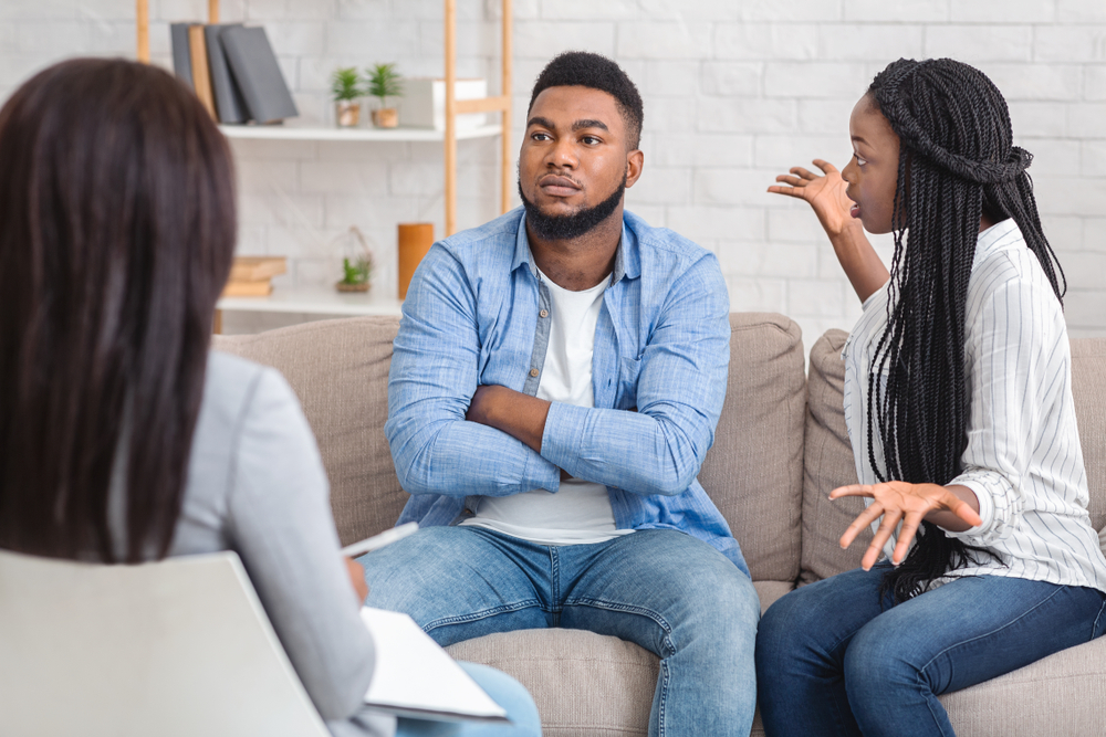 Disappointed afro wife blaming her indifferent husband during marriage therapy counselling session(Prostock-studio)s