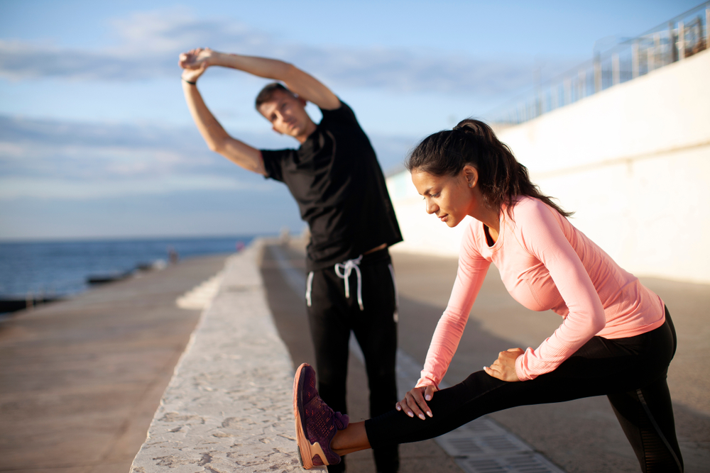 Happy fit young couple working out, warming up and stretching outdoor(dkovalenko)s