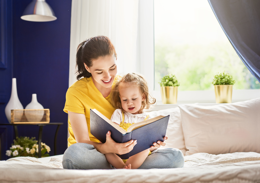 Pretty young mother reading a book to her daughter(Yuganov Konstantin)s