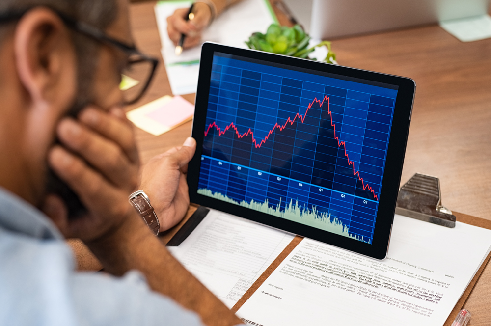 Close de um corretor do mercado de ações, trabalhando com gráficos em tablet digital no escritório.  Vista traseira do agente de estoque lendo relatório e gráfico ruins.  Vista traseira do empresário multiétnico, analisando as vendas de outono.