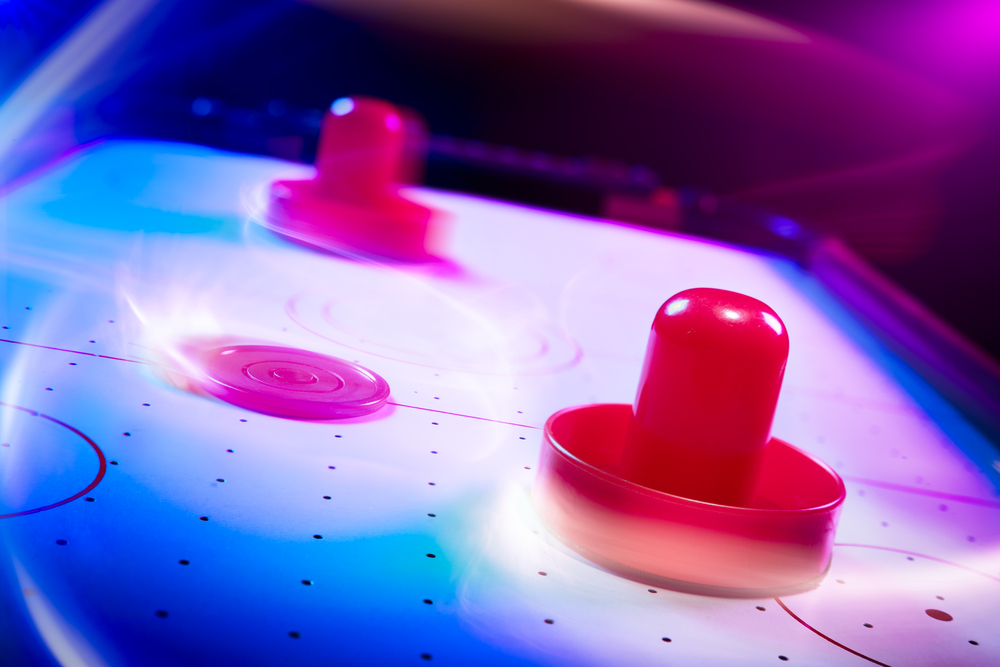 Mesa de air hockey com iluminação dramática e trilhas de movimento (Fer Gregory) s
