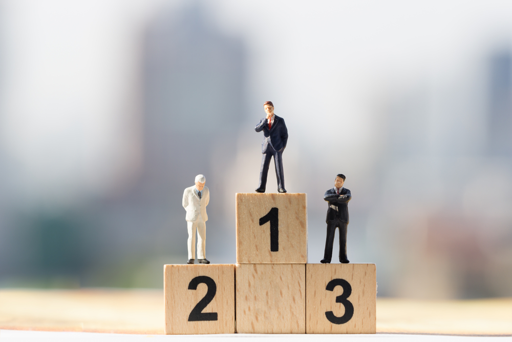 Small businessmen figures standing on wooden podium 1, 2, 3 with cityscape background(Khongtham)s