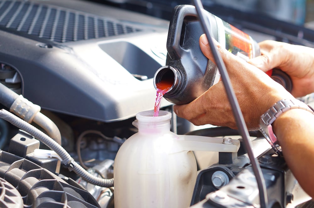 mão masculina que enche o sistema de refrigeração do carro com refrigerante (SiNeeKan) s
