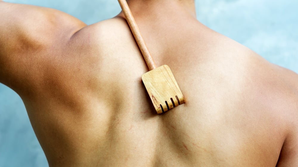 Homem coçando as costas com um arranha-costas de madeira (Supaleka_P) s