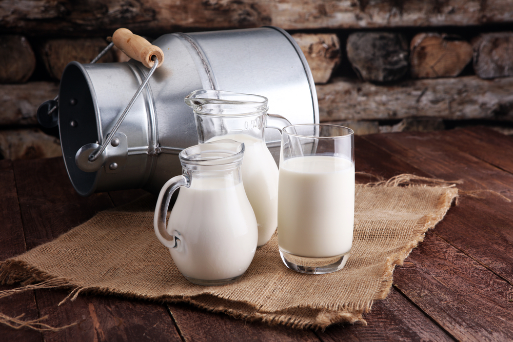 Uma jarra de leite e um copo de leite em uma mesa de madeira (beats1) s