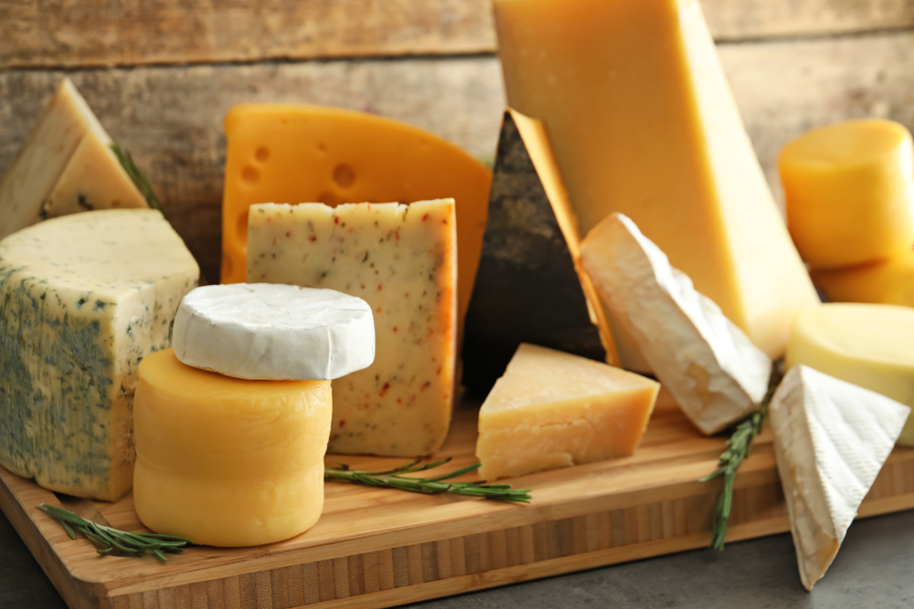 Wooden board with different kinds of delicious cheese on table(Africa Studio)s