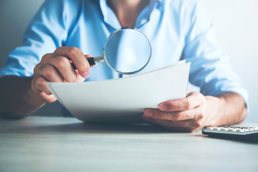 Businessman looking through a magnifying glass to documents(Tiko Aramyan)s