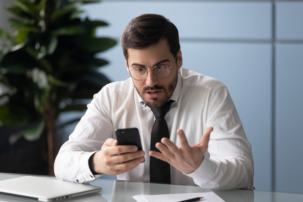 Businessman holds gadget feels annoyed with broken phone(fizkes)s