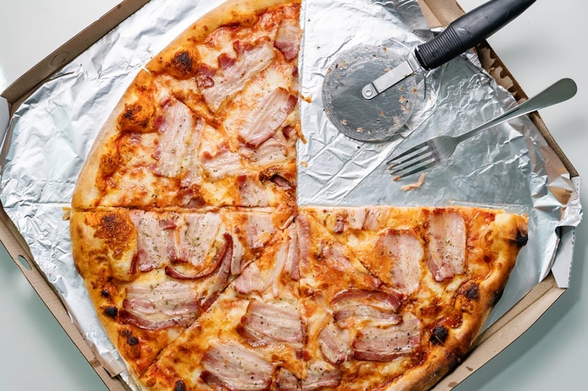 Feche a pizza de bacon e queijo com duas fatias de um quarto tiradas com garfo de metal (Miljan Zivkovic)S