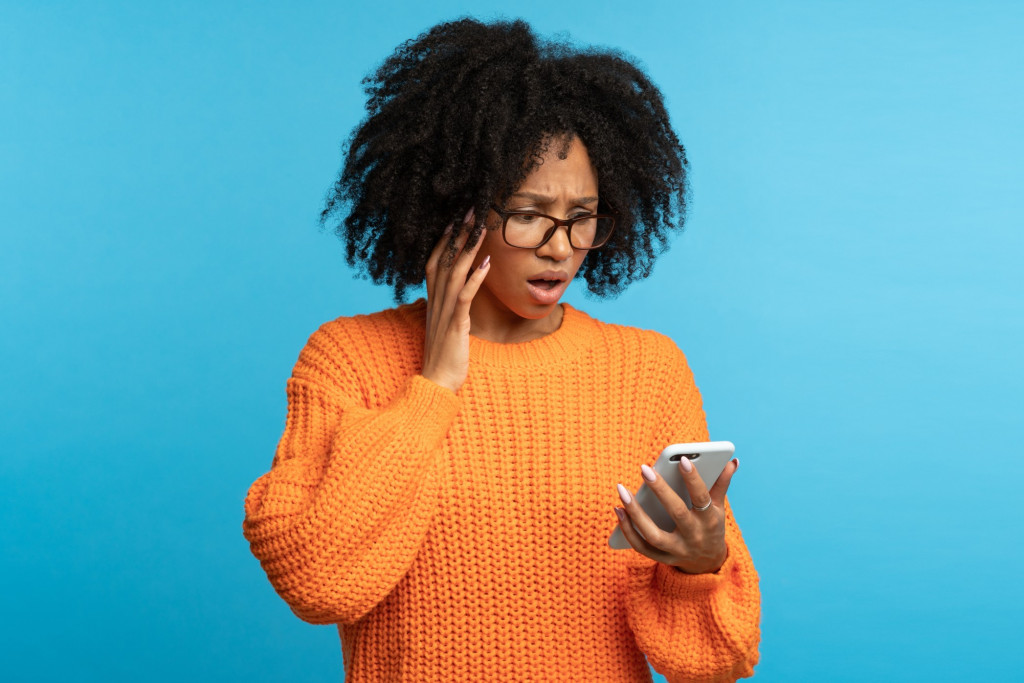 studio-portrait-of-confused-shocked-african-ethnicity-woman-looking-at-smartphone-with-opened-mouth_t20_nLa6L7