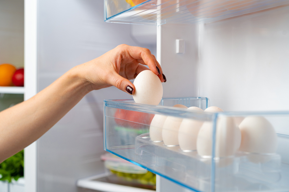 Female hand taking egg from a fridge close up