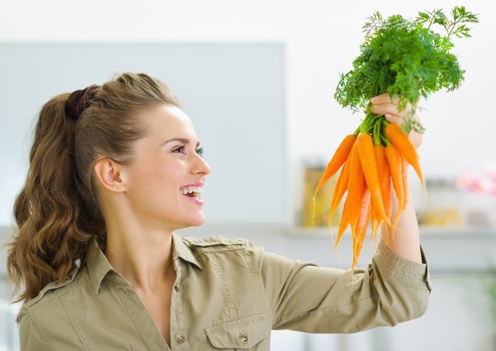 Happy,Young,Housewife,Holding,Carrots,In,Kitchen