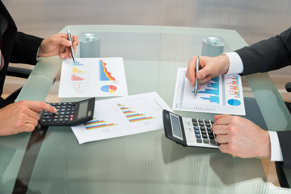 Close-up,Of,Two,Businessmen,Analyzing,The,Graph,Using,Calculator,On