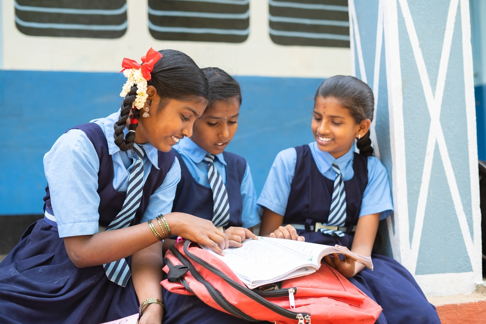 Gorup,Of,Girl,Kids,Studying,From,Book,At,School,Corridor