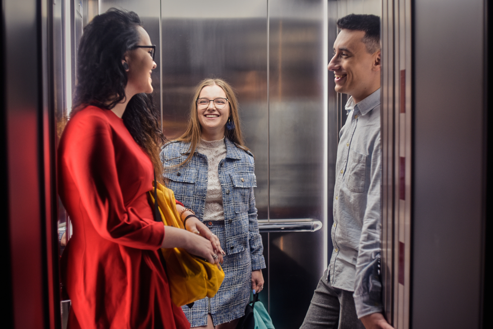 The girls and the guy ride in the elevator. Students go to study. People in the elevator. Elevator with people, communication in public places.