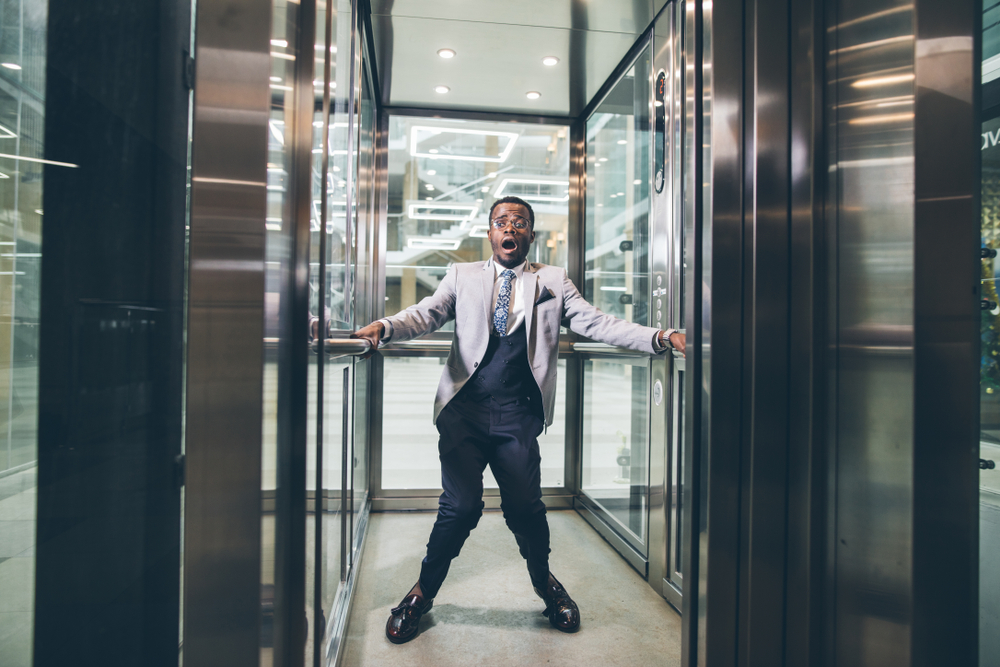 african Businessman screaming in the elevator. fear claustrophobia concept