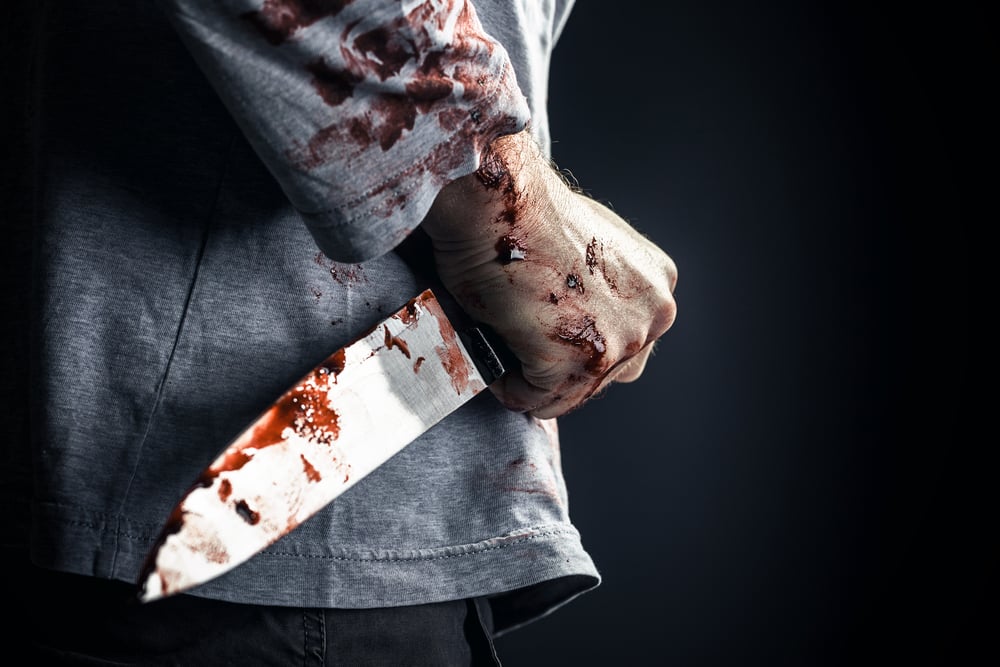 detail of man holding bloody knife crime concept