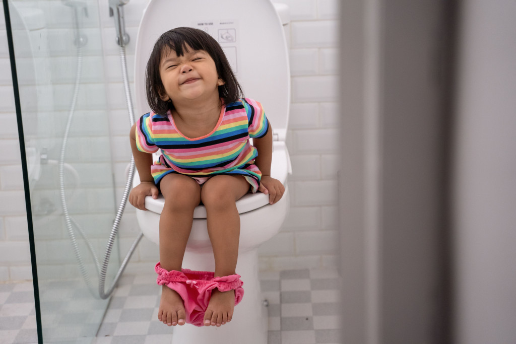 pooping in the toilet. asian kid push it hard while sitting on toilet