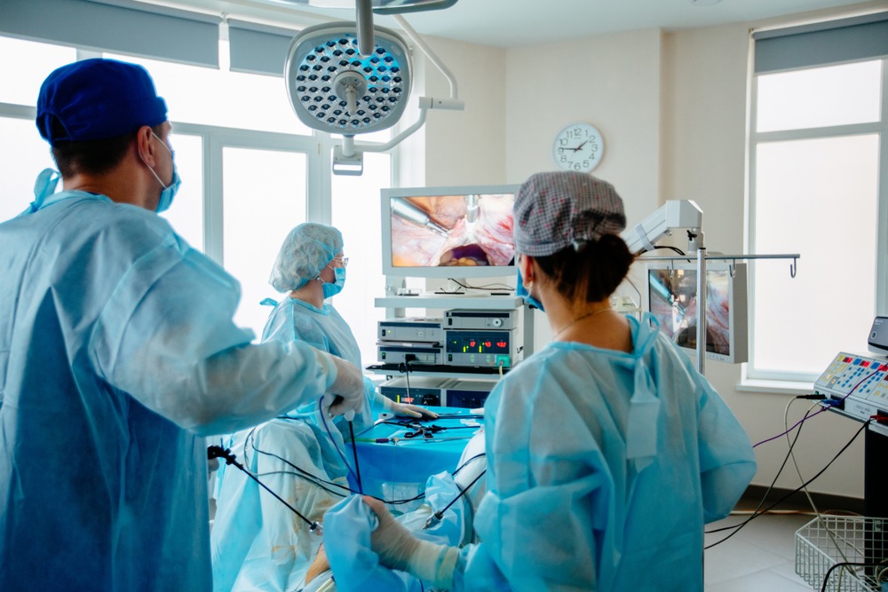 Back,View,Of,Surgeons,Team,Looks,At,Monitors,While,Preforming