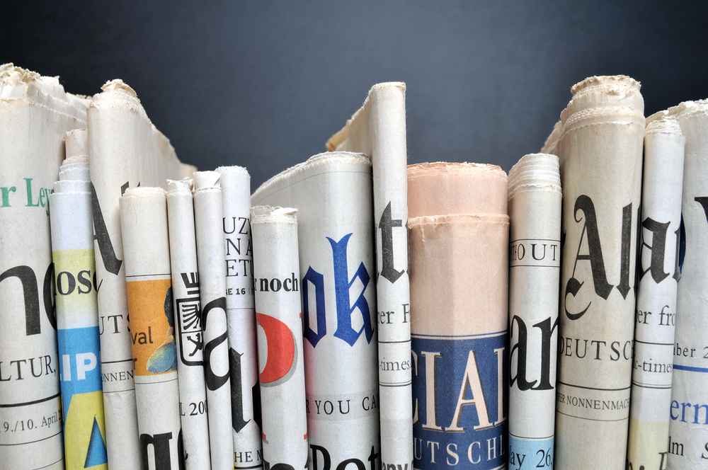 News,-,Folded,Newspapers,In,Front,Of,Black,Wall